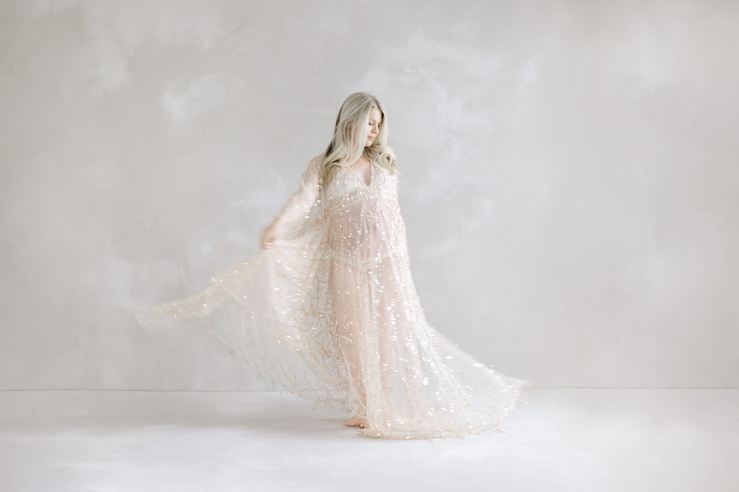 motherhood portrait of expectant mother twirling in a beautiful sparklin gown